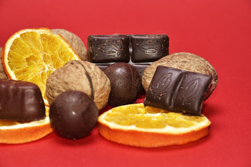 Chocolate , orange and nuts on red background
