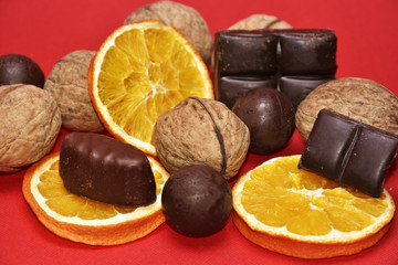 Chocolate , orange and nuts on red background