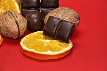 Chocolate , orange and nuts on red background