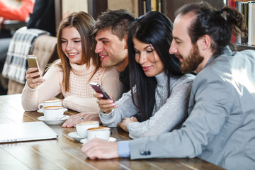 Group of friends with coffee and looking at smartphone
