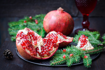 Pomegranate with festive decorations over wooden background