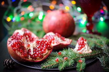 Pomegranate with festive decorations over wooden background