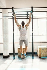 Composite image of rear view of man doing pull ups