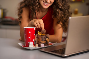 Fototapeta premium Woman having cup of hot chocolate with cookies and using laptop