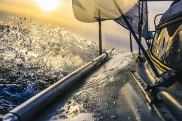 Selbstklebende Fototapete Segeln Segelboot fährt schnell bei Sonnenuntergang