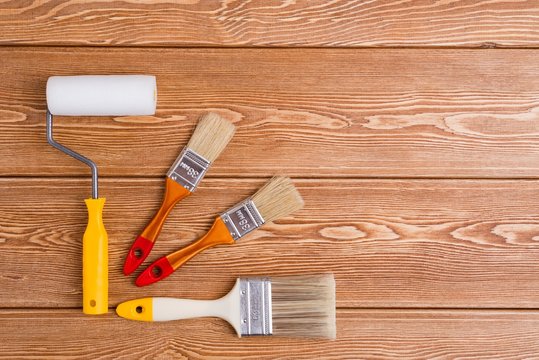 Paint brushes and roller on a wooden background 