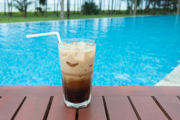 Iced coffee on the table beside the pool