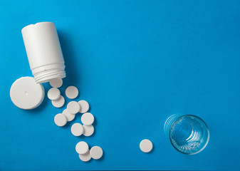 Effervescent pills coming from a white tube on a blue surface, n - obrazy, fototapety, plakaty