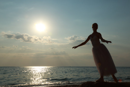 dancing ballerina  at sunset on the coast
