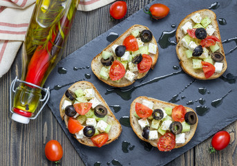 Greek style crostini with feta cheese, tomatoes, cucumber, olives and herbs, top view