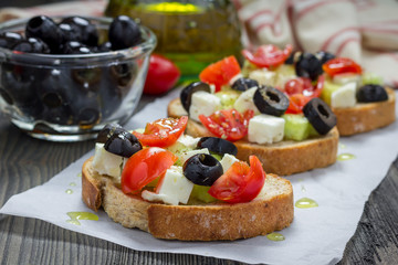 Greek style crostini with feta cheese, tomatoes, cucumber, olives and herbs