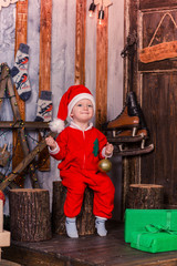 Happy little baby in Santa's costume near Xmas tree