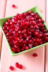 pomegranate seeds in a bowl on wooden surface