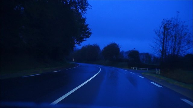 Fahrt mit dem PKW &uuml;ber eine Landstra&szlig;e in der blauen Stunde