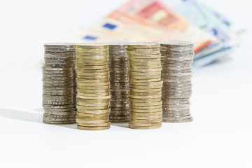 coins of 2 and 1 euros stacked and euro banknotes on a white background
