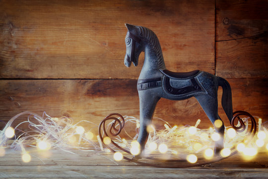 image of rocking horse and magic christmas lights on wooden table

