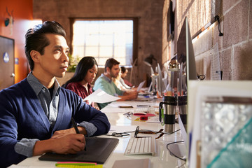 Designers Working At Desks In Modern Office