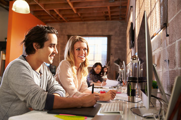 Designers Working Together At Desks In Modern Office