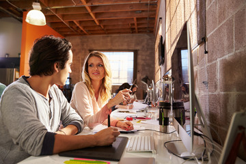 Designers Working Together At Desks In Modern Office