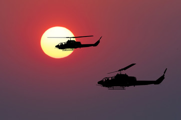 Two flying army helicopters on sunset background
