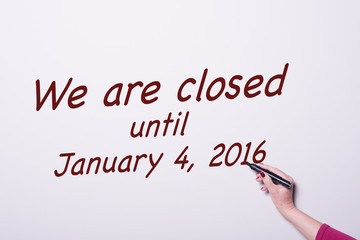 Fototapeta premium woman's hand with pen on whiteboard writing we are closed