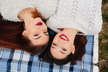 Two beautiful girls lie on the bench