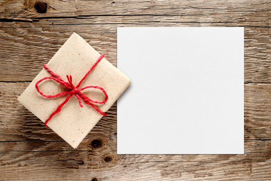 Gift box and white blank paper on wooden background