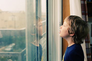 Cute 8 years old autustic boy looking at the rain