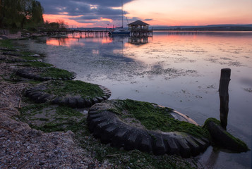 Stunning sunset on the lake with tires on the beach.