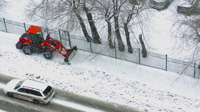 Bright red tractor clears the sidewalk