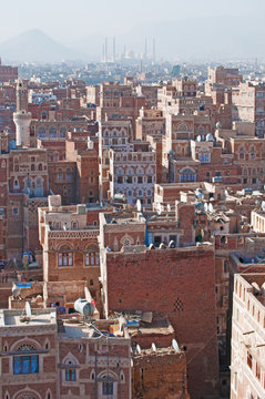 La città vecchia di Sana'a, Yemen, case decorate, palazzi, minareti e la moschea Saleh sullo sfondo, nella nebbia