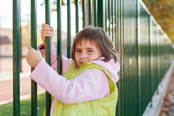 young girl is holding a metal fence