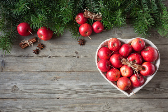 Wooden background with red apples and fir branches