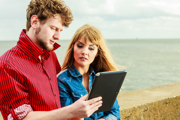 Young couple with tablet by seaside outdoor