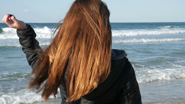 Girl with long red hair on the beach