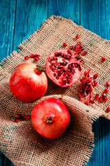 
useful fruit, ripe , juicy and fresh pomegranates on sacking on a wooden background