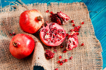 
useful fruit, ripe , juicy and fresh pomegranates on sacking on a wooden background