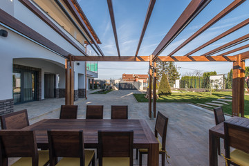 Wooden table and chairs on open terrace in modern villa house