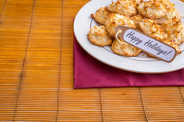 Fresh baked coconut macaroons with happy holidays tag.