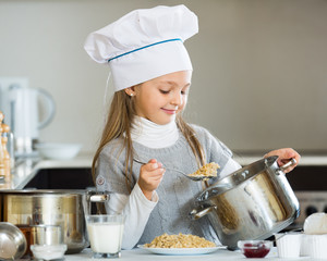 Sweet girl preparing oatmeal for breakfast in kitchen