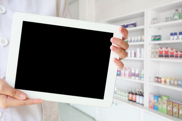 female pharmacist using tablet pc against close up of shelves of