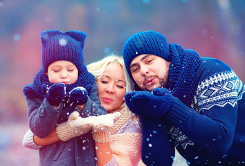 portrait of happy family blowing winter snow outdoors