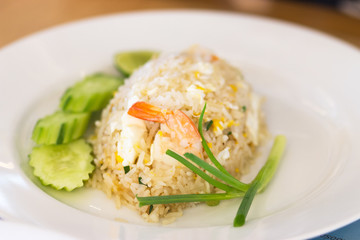 shrimp fried rice with cucumber and spring onions on a white pla