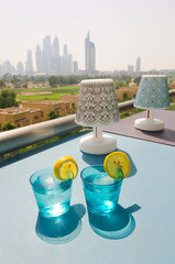 Ice cold drink with a slice of lemon with the dubai marina skyline view, from a balcony