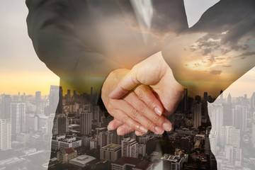 Double exposure of handshake and Cityscape sunset