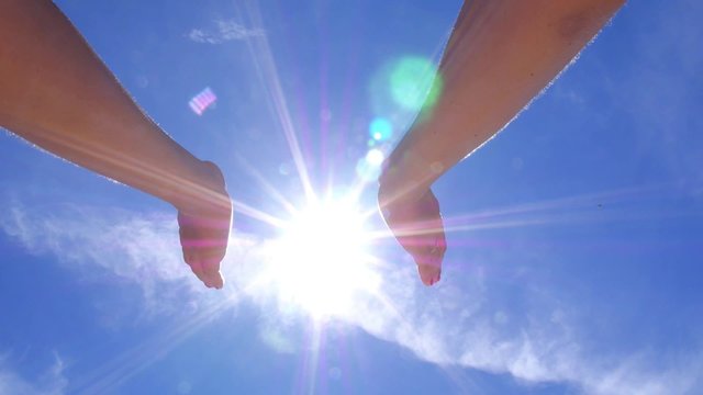 Female Hands Holding the Sun in Blue Sky. 