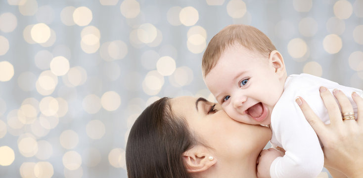 happy mother kissing her baby over lights