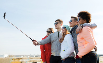 friends taking selfie with smartphone on stick