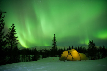 beleuchtetes Zelt mit Nordlichtern im Hintergrund