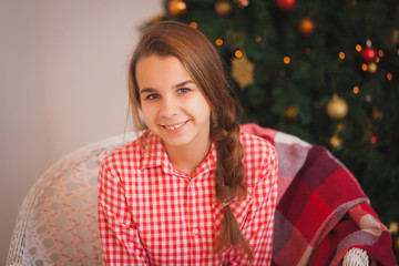 Teen girl with pigtails in a red plaid shirt in Christmas decorations